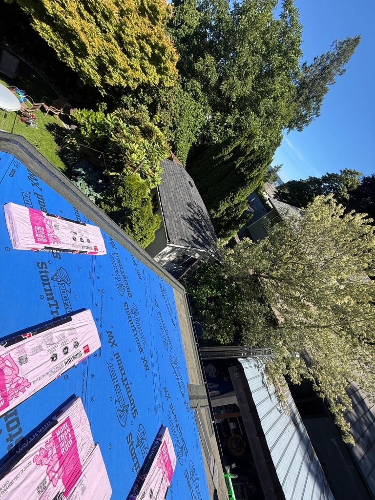 Roof during tear-off — underlayment and shingle bundles visible